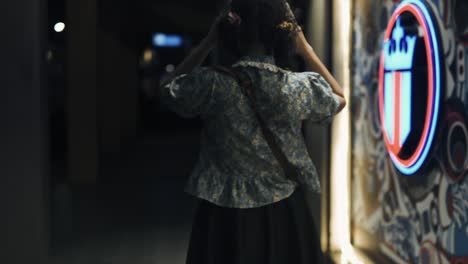 a woman walking at night past neon shop signs