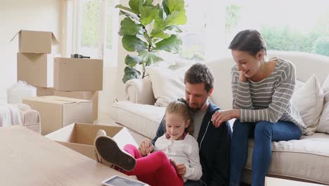 Family-sitting-and-using-a-tablet-in-their-new-home-4K-4k