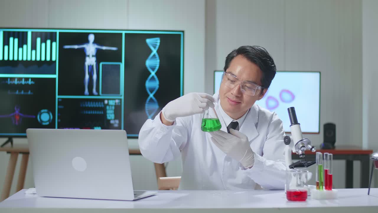 Young Asian Male Research Scientist Looking  Glass Test-Tube And Warmly Smiles Into The Camera