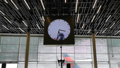 amsterdam airport lounge, huge clock being cleaned by man in blue overcoat.