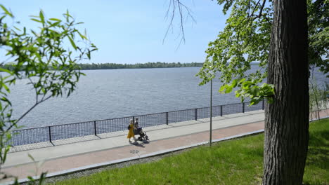 couple walking with baby stroller by the river