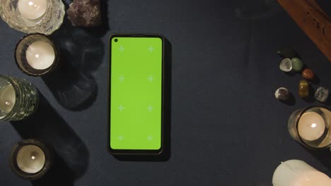 fotografía aérea de una persona que hace una lectura de tarot con un teléfono móvil de pantalla verde en la mesa 1