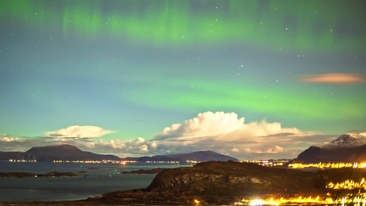 toma de lapso de tiempo de 5.000 metros de la hermosa iluminación de la ciudad de alesund y la aurora boreal en el cielo azul - nubes moviéndose sobre las montañas en el fondo