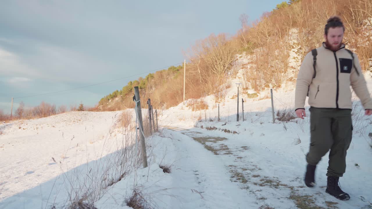 화창한 날 산 근처의 눈으로 뒤덮인 오솔길을 걷고 있는 노르웨이 남자