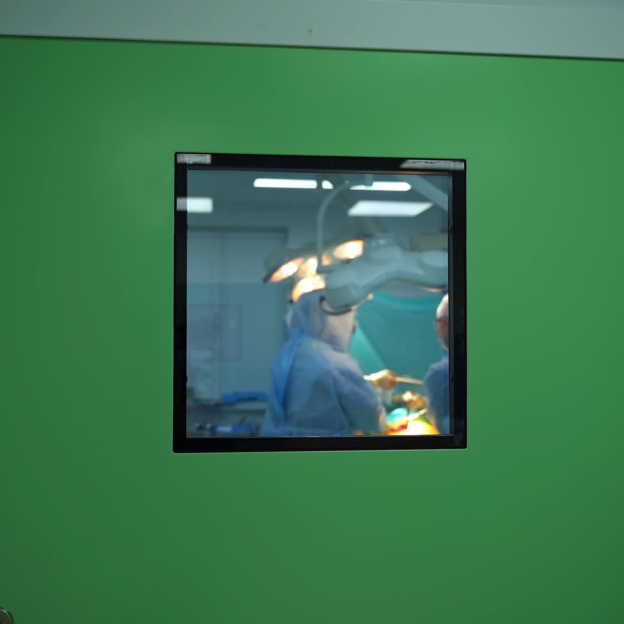 Operation in hospital. View through the window on surgical process with group of specialists. Medical concept.