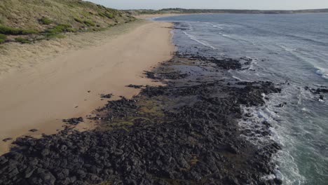 Phillip-Island-With-Tourist-Woman-Walking-On-The-Shore-In-Victoria,-Australia---aerial-drone-shot