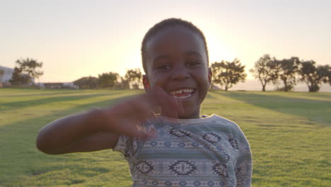 African-elementary-school-boy-waving-to-camera-outdoors