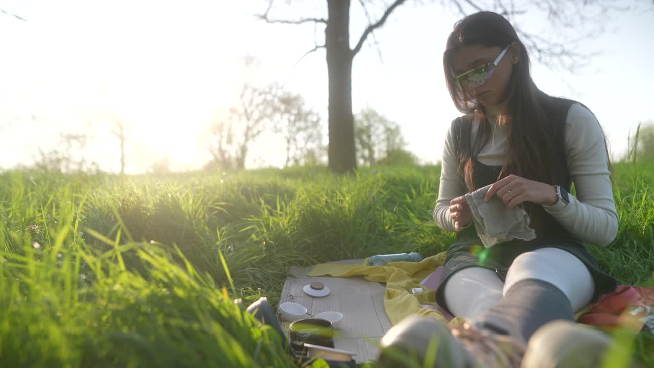 Woman enjoying a tea ceremony in a park at sunset
