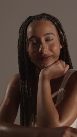 fotografía de belleza en el estudio de una joven sonriente con el pelo largo trenzado contra un fondo neutral 5