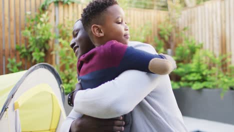 video of happy african american father and son hugging in garden