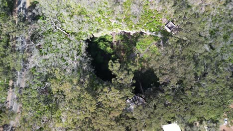 Drop-down-view-of-a-cave-top-entrance-during-the-day-by-drone-in-Australia