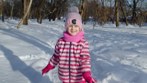 Smiling-child-kid-running,-having-fun,-dancing,-fooling-around-on-snowy-road-in-winter-park-forest