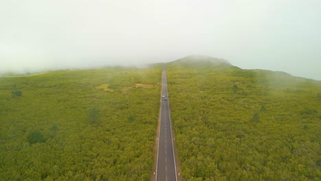 aerial birds eye shot of mountain road with driving cars during foggy day in madeira , portugal