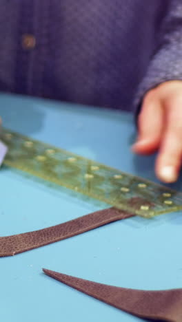 mid-section of craftswoman cutting leather