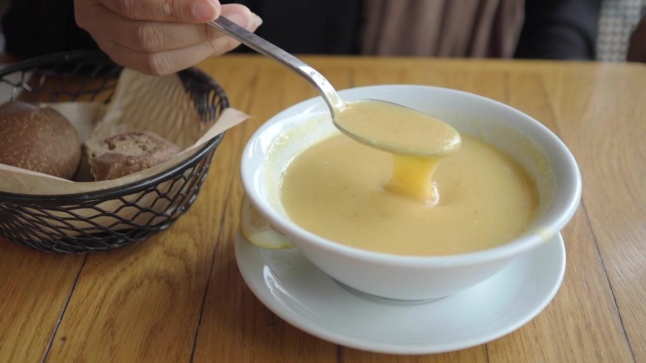 Person Eating Creamy Soup in a Restaurant