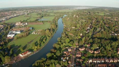 aerial shot over river passing through residential area uk