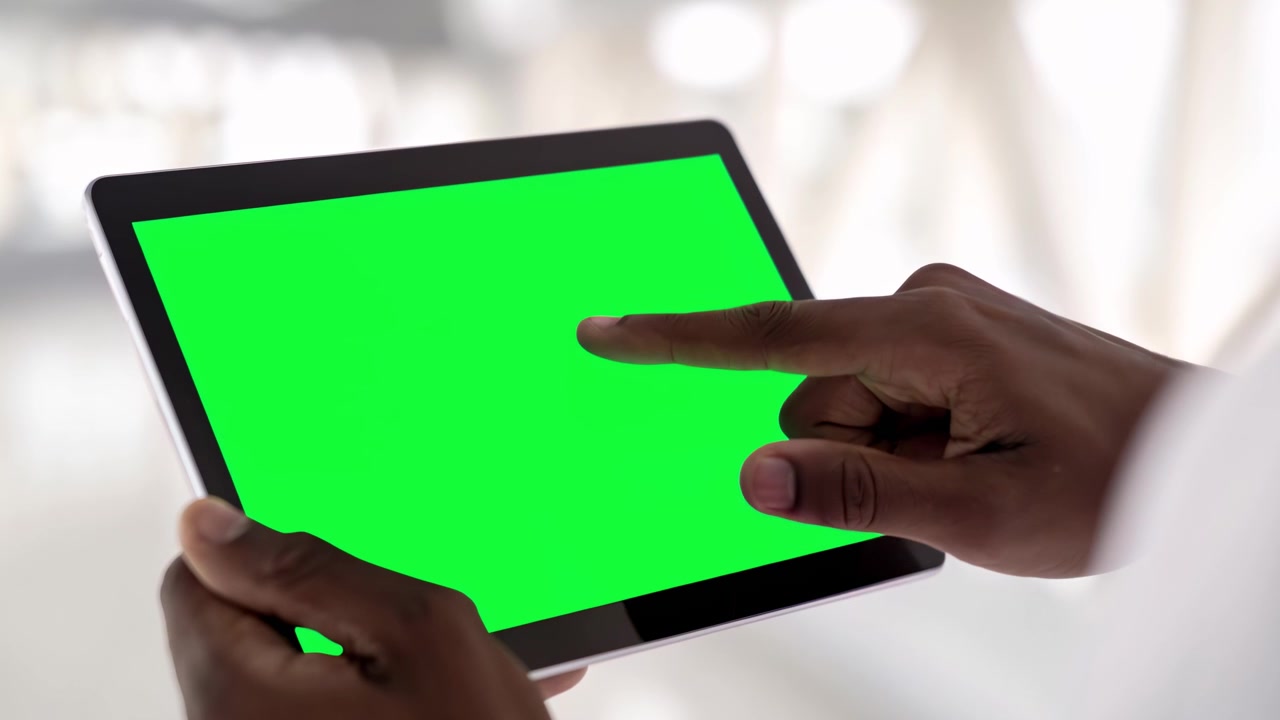 Person Using Tablet with Green Screen in Bright Office