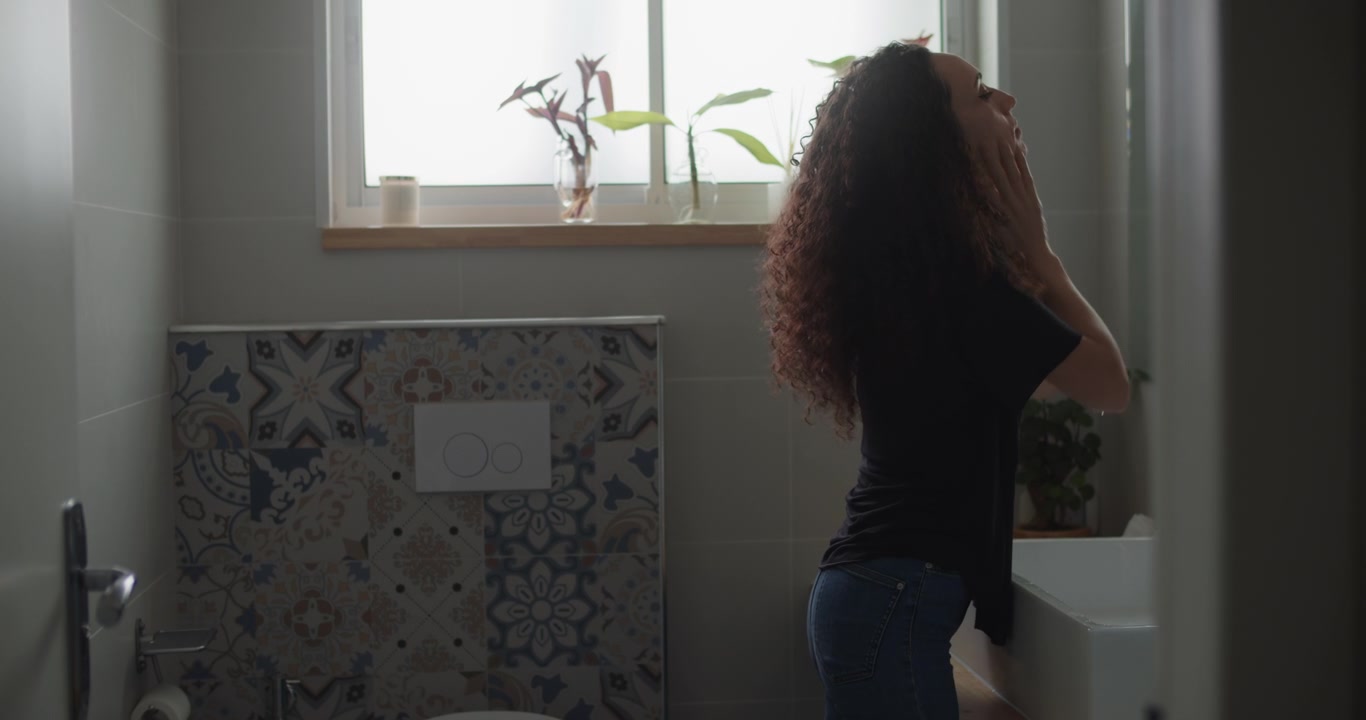 Young woman washing her face with water