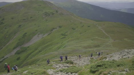 group of hiking tourists with backpacks trekking in mountains.