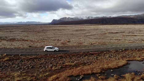 toma de perfil amplio de un automóvil conduciendo por un camino de tierra en islandia