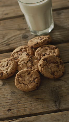 video vertical de galletas de chispas de chocolate y un vaso de leche sobre un fondo de madera