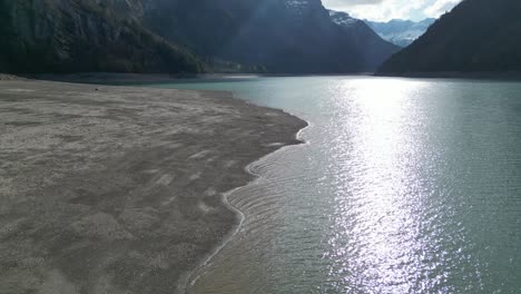 aerial forward view of shoreline of an alpine lake in a fantastic mountain landscape