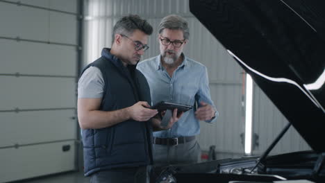 mechanic and customer discuss car repair in an auto service garage
