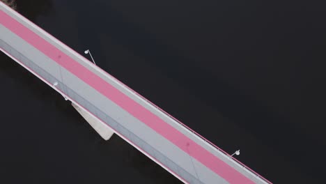 A-drone-advances-forward,-altering-its-elevation-and-angle-to-showcase-a-striking-bridge-with-vivid-pink-stripes