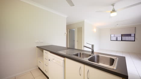 empty kitchen and vacant lounge area with small thin sink and dishwasher in apartment building