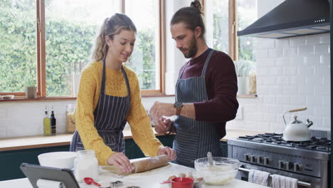 una pareja feliz horneando galletas de navidad en la cocina de casa, en cámara lenta.