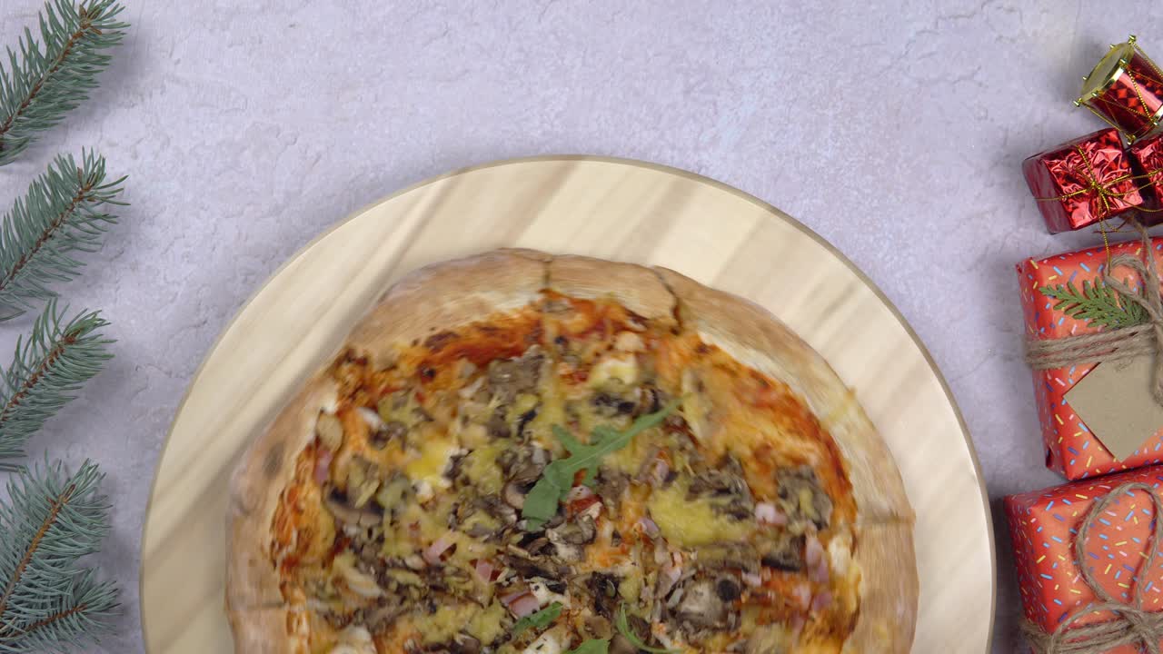una capa plana de pizza girando una rotación de 360 grados en un salvador de madera, con decoraciones navideñas a su alrededor.