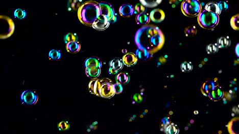 soap bubbles fly and fade in different colors black background soap bubbles fly and flicker with blue green and orange colors black background