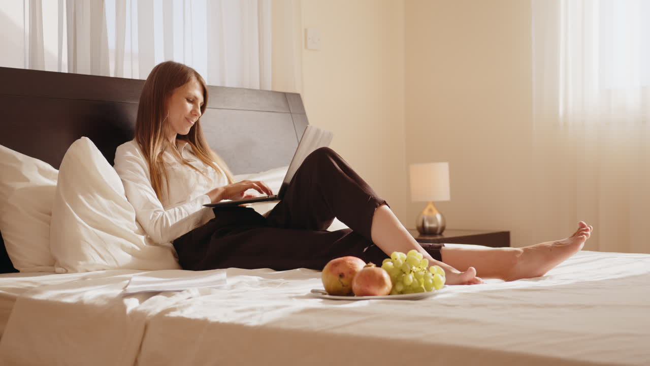 침대에 노트북으로 일하는 여자