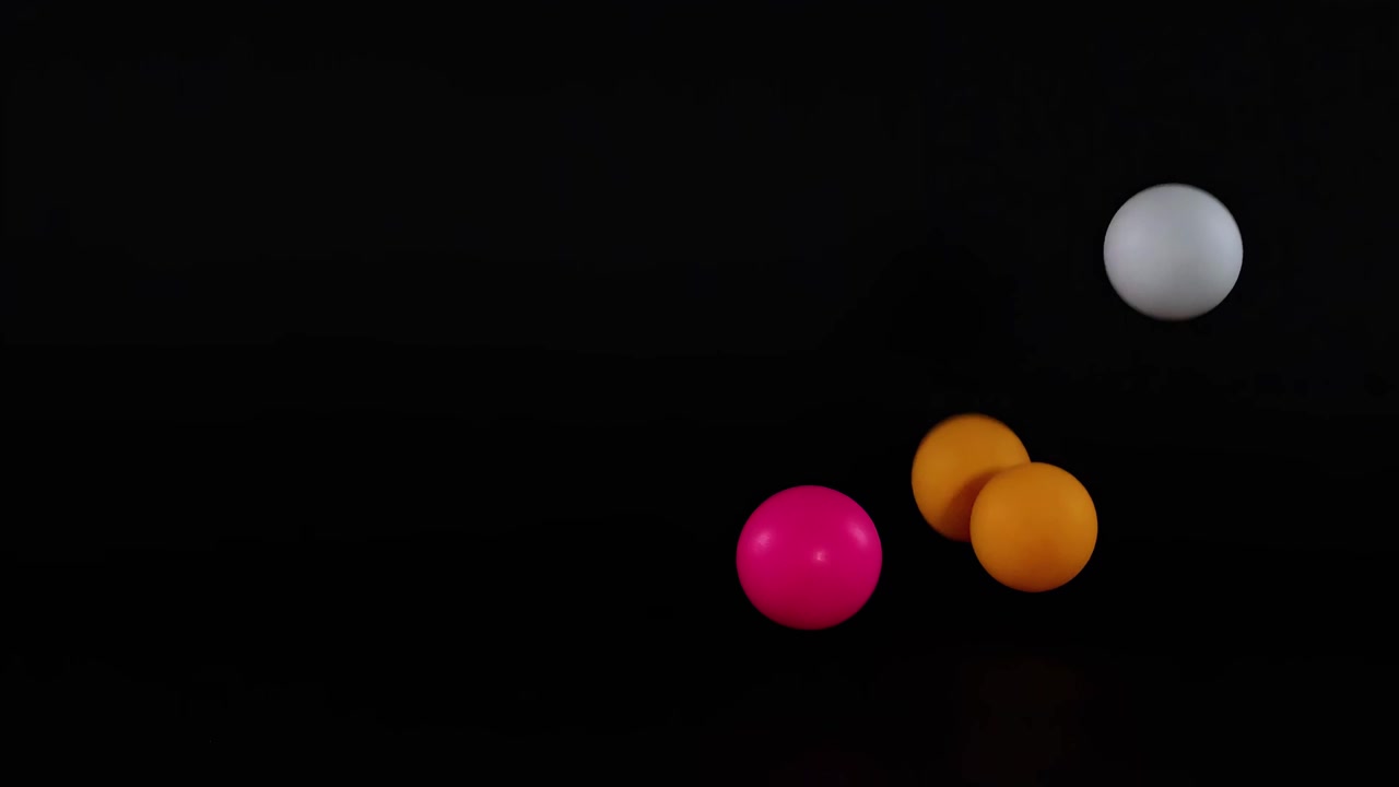 Colorful balls dynamically bounce against a dark backdrop, showcasing vibrant motion and contrast.