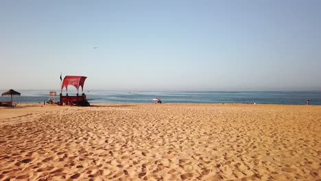 Villamoura-beach-in-The-Algarve-Portugal-with-life-guard-station-and-lonely-parasol-nearing-the-end-of-the-day