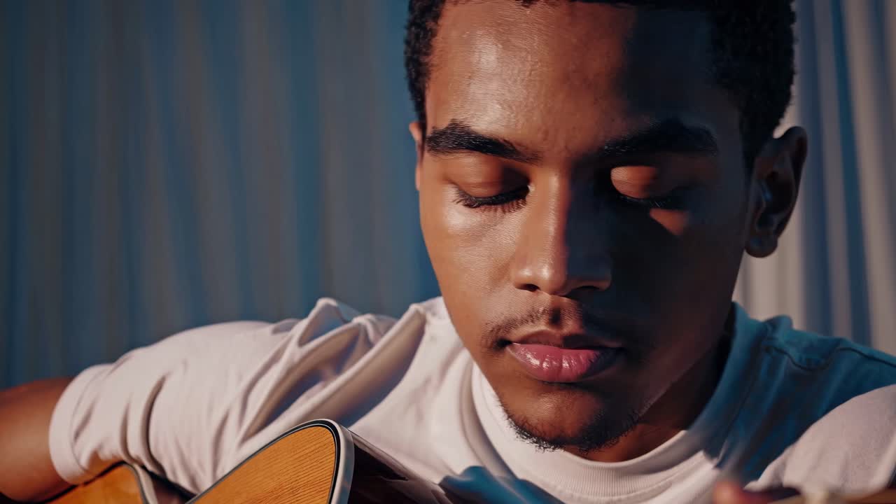Close-up de um jovem tocando violão, capturando um momento íntimo e sereno com suavidade