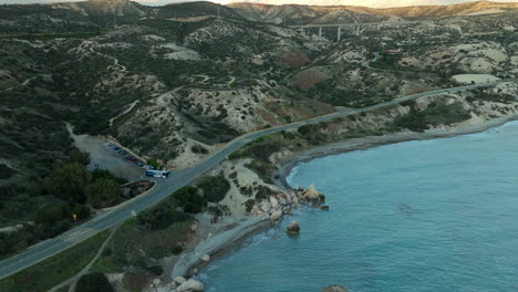 aerial view of a coastal road near aphrodite's rock in cyprus, winding along the shoreline and hilly terrain