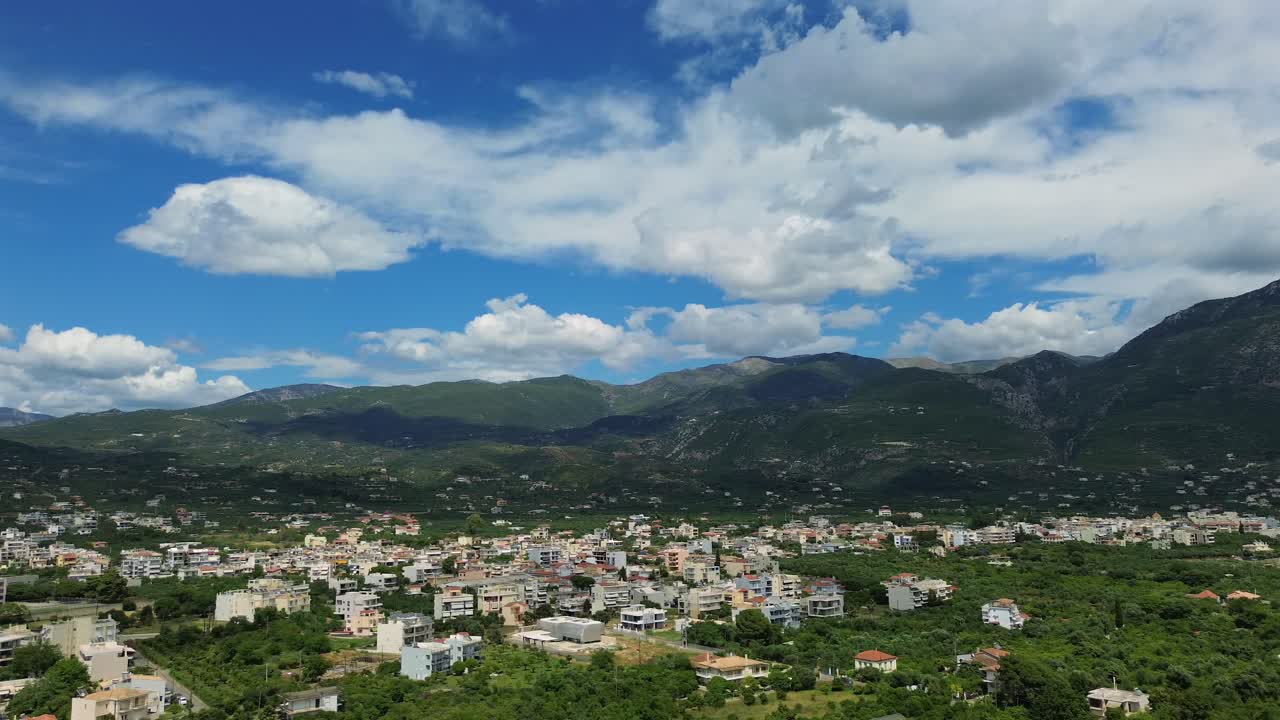Aerial wide panoramic view of eastern suburbs of Kalamata city, beautiful blue sky with white cloud formations on a spring day 4K