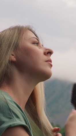 mujer pensativa bastante cepilla el cabello largo de pie contra las montañas brumosas en el complejo de tierras altas en la mañana nublada vista lateral en cámara lenta