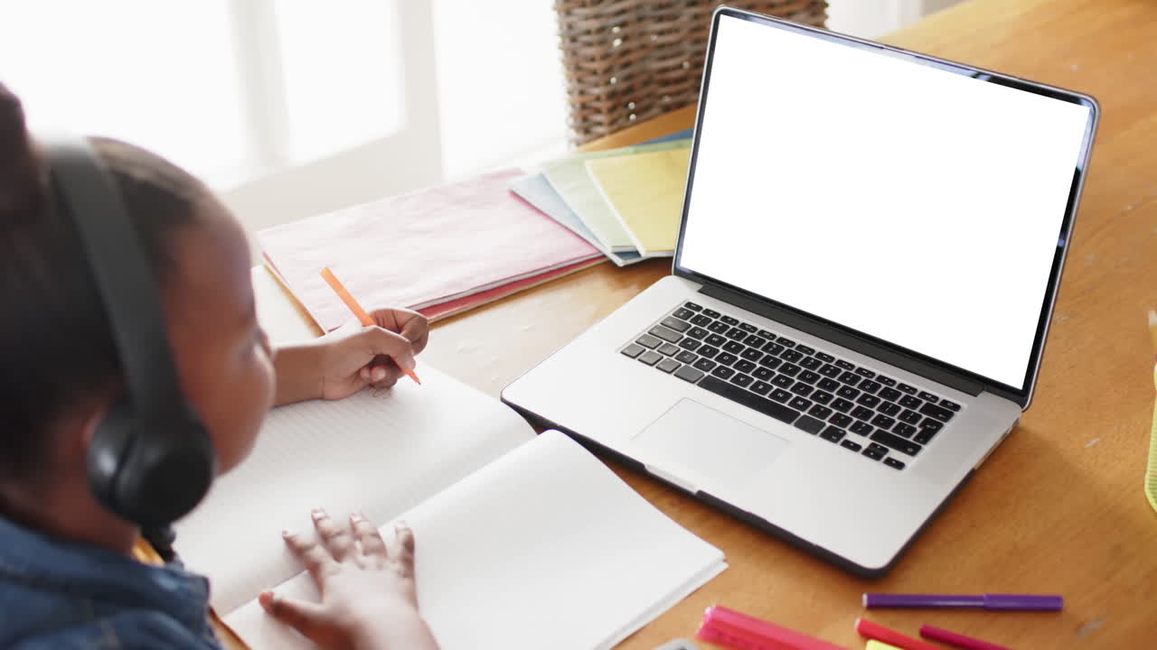 escolar afroamericana teniendo clase en la llamada de video portátil con espacio de copia en cámara lenta