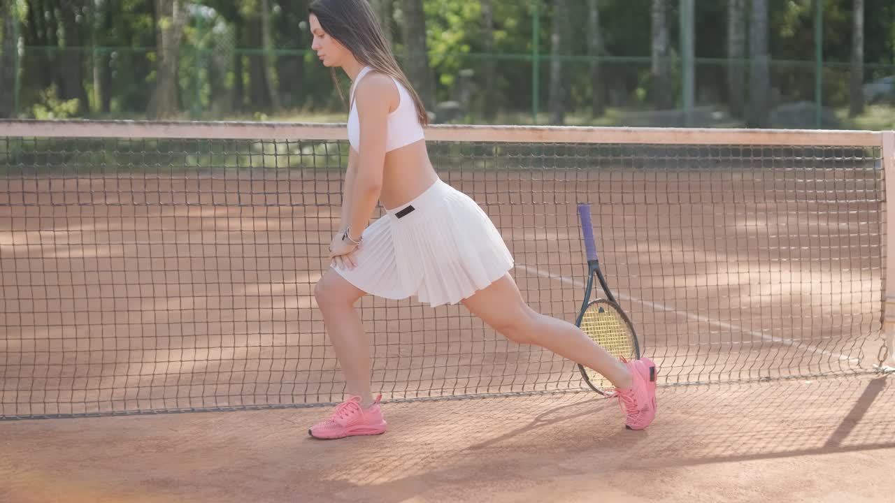 코치와 함께 야외 코트에서 테니스를 연습하는 젊은 여성. 코치는 선수가 그녀의 기술에 대해 일하면서, 운동 훈련 세션에서 그녀의 스트로크를 완성하는 동안 지침을 제공합니다.