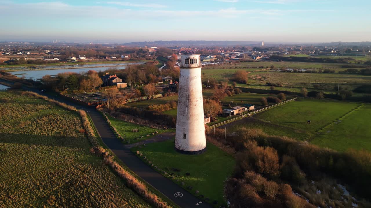 Beautiful aerial drone anti-clockwise pan and pull back of Leasowe Lighthouse, revealing scenery at sunset in winter, UK