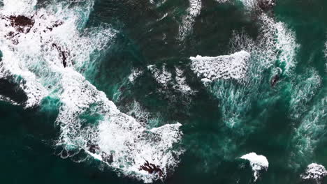 drone parallax shot of violent and powerful waves crashing onto the rocks on a windy and overcast day on the coastline of hawaii