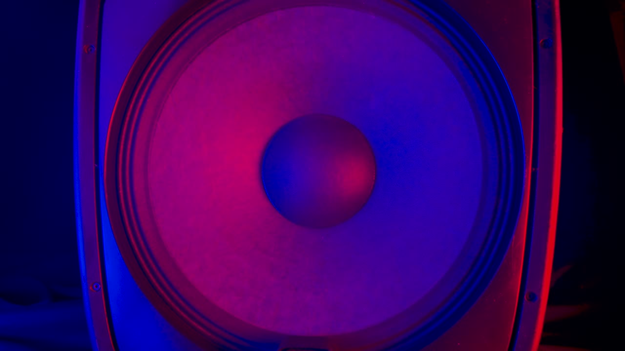 tocando membranas de altavoces iluminadas por coloridas luces de neón de discoteca. poderosos altavoces modernos vibran rebotando al ritmo de la música electrónica. cerca. movimiento lento