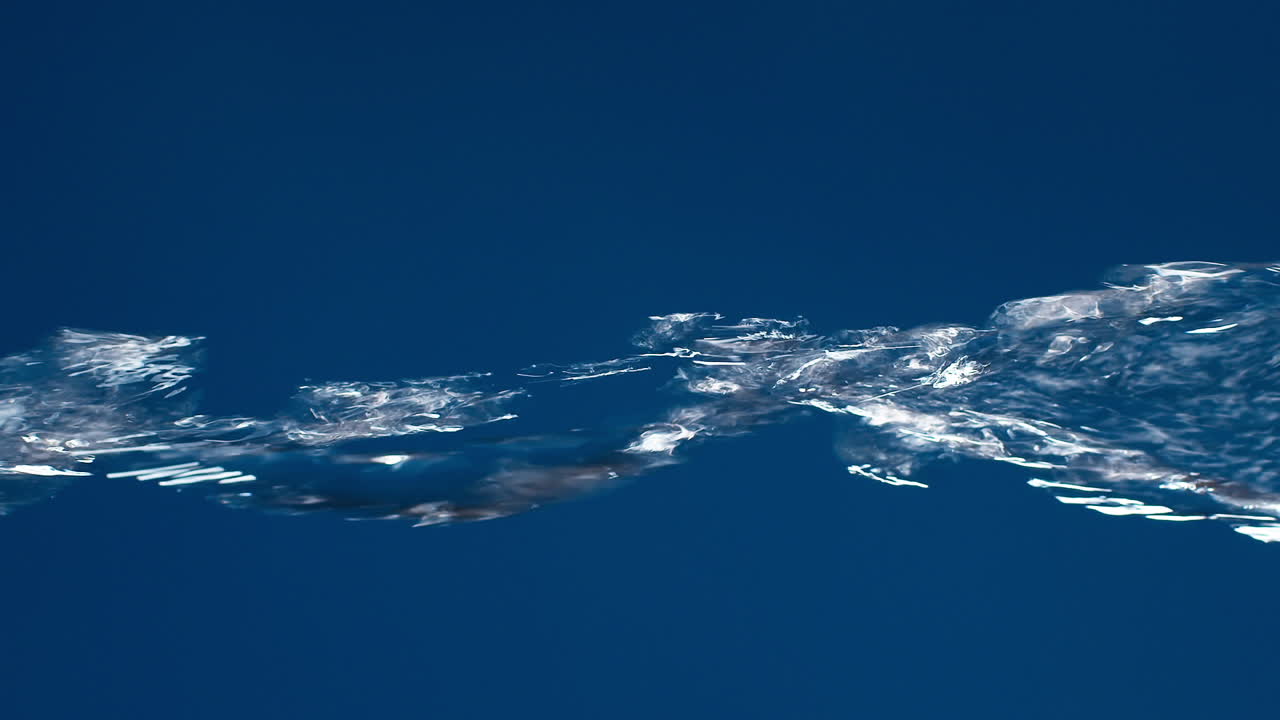 슬로우 모션으로 촬영하는 파란색 배경에 물이 튀면서 흐르는 진짜 순수한 물의 수직