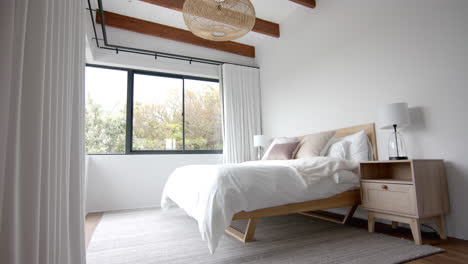 interior of domestic bedroom with double bed and window overlooking garden, copy space, slow motion