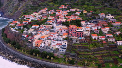 aerial view of small village with beautiful houses on crashing waves against shore on coastline