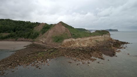 Aerial-drone-shot-over-Cayton-bay,-Scarborough-in-the-distance,-North-Yorkshire-on-a-cloudy-day