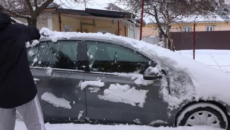 Man-Brushing-The-Snow-Off-His-Car---medium-shot