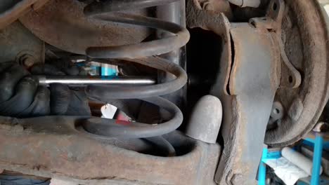 mechanic changing rear brakes and wheel bearing closeup showing suspension